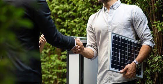 men shaking hands while one is holding solar panel - commercial solar faq pic