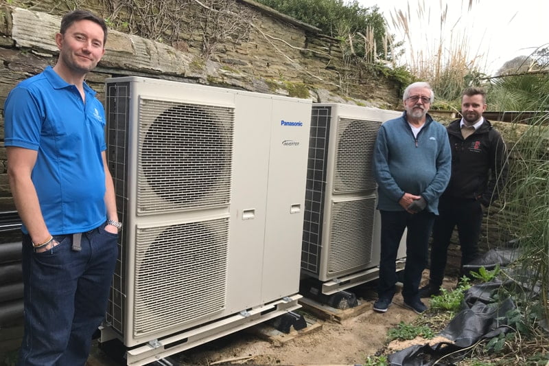 air source heat pumps with installers standing beside