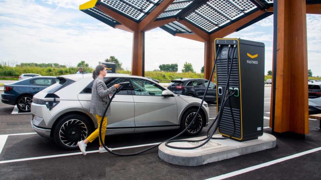 woman holding ev chargers pump with her ev car